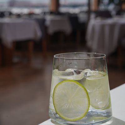 A glass of water with a slice of lime on a wooden table.